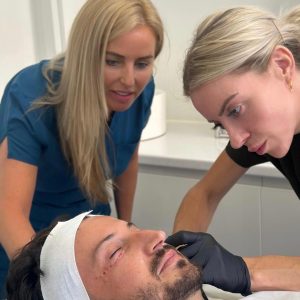 Two Valessa Aesthetics Institute trainers treating a male live model's face in the Liverpool training clinic